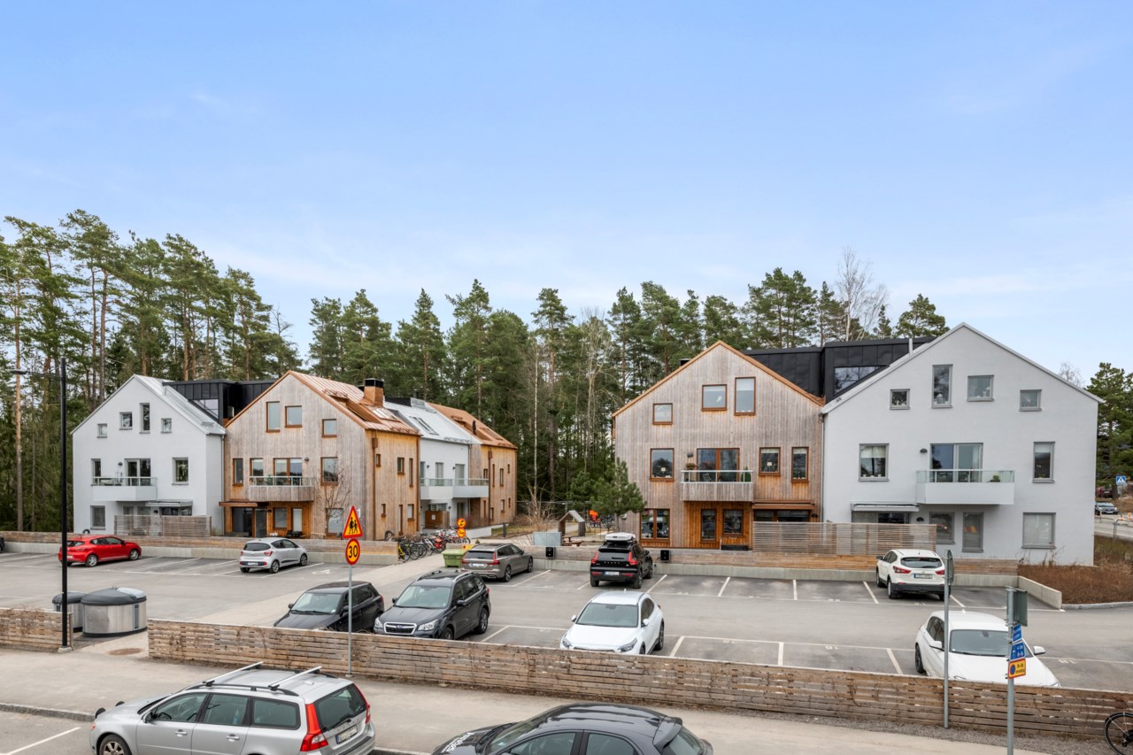 Husen framifrån med parkering intill